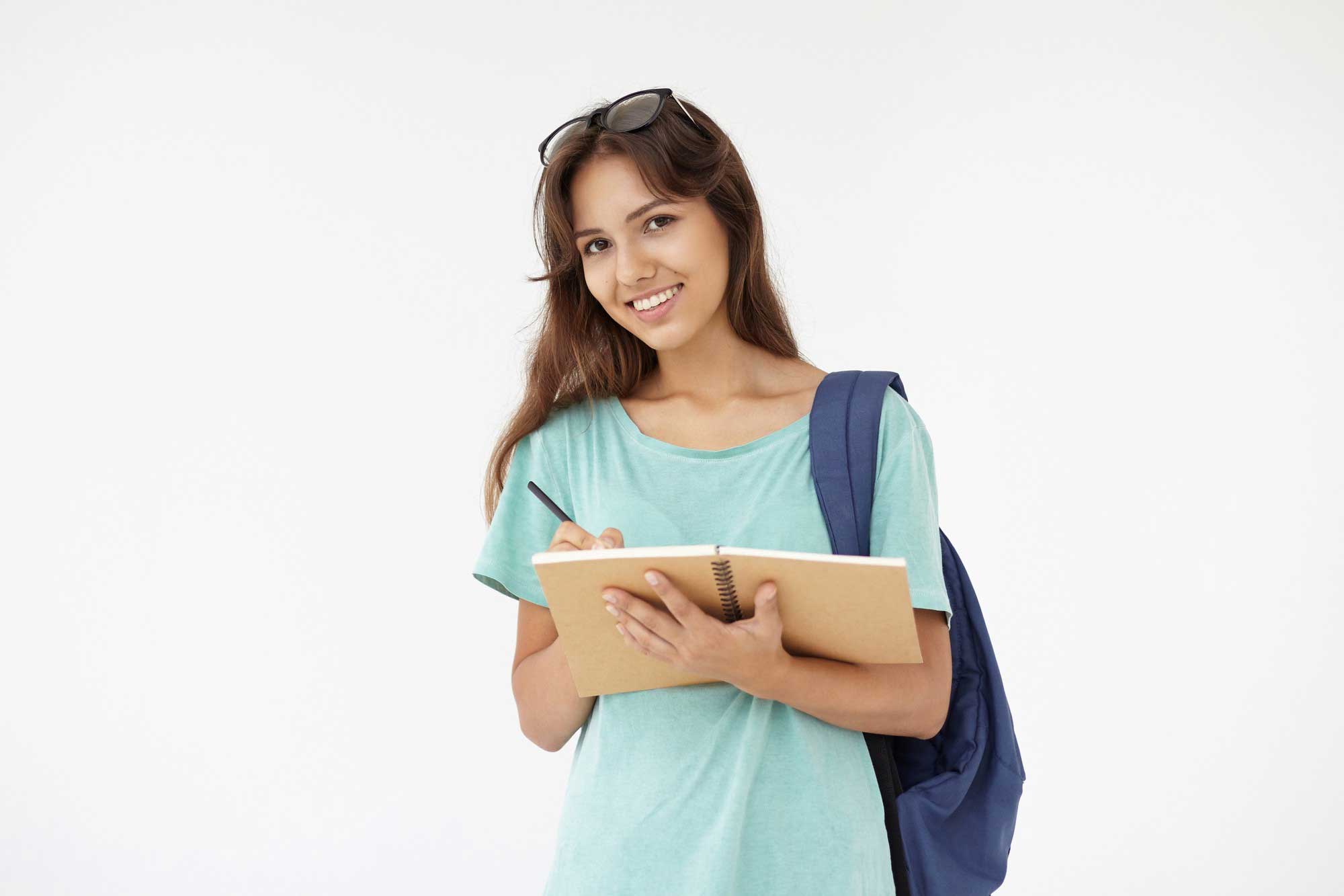 Imagen de una estudiante de pie con una libreta en sus manos